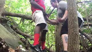 A blonde woman gives oral sex to a black man in the woods